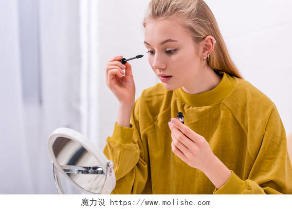 年轻妇女照镜子用睫毛膏